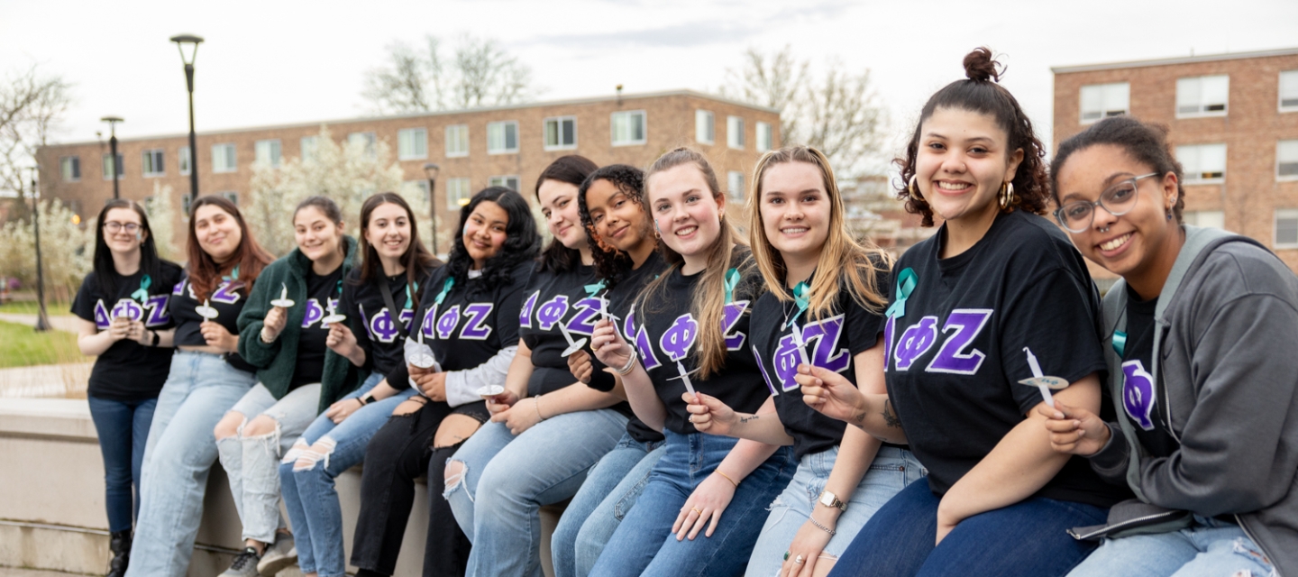 Sorority sisters sitting on ledge lighting candles for rememberance.